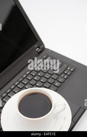 Tasse de café sur le dessus d'un ordinateur portable noir Banque D'Images