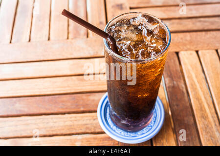 Soda noir frais avec de la glace sur la table en bois Banque D'Images