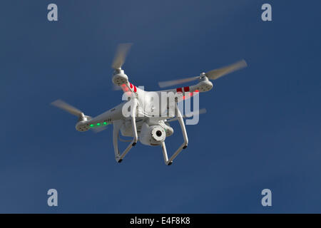 Petit hélicoptère sans pilote avec un appareil photo flottant dans le ciel bleu Banque D'Images