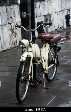 Un vieux cyclomoteur enchaîné à un poteau sur une rue de Cracovie. Banque D'Images