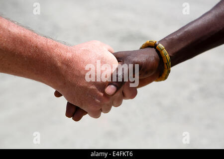 Poignée de main entre un Blanc et un Africain sur fond gris Banque D'Images