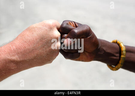 Poignée de main entre un Blanc et un Africain sur fond gris Banque D'Images