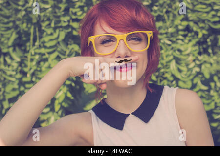 Cute girl hipster avec moustache à la main sur un doigt elle placée sur ses lèvres, mignon et drôle. Couleurs rétro Banque D'Images