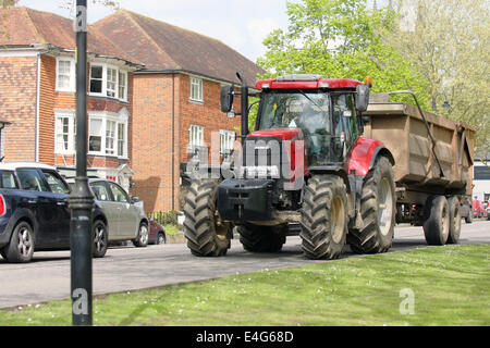 Un tracteur tirant un plein chargement de fumier dans la petite ville rurale d'Ashford, Kent, Angleterre Banque D'Images