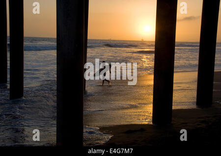 Surfer en vertu de la Huntington Beach Pier Banque D'Images