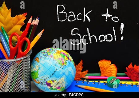 Retour à l'école écrit sur un tableau noir avec des fournitures scolaires Banque D'Images