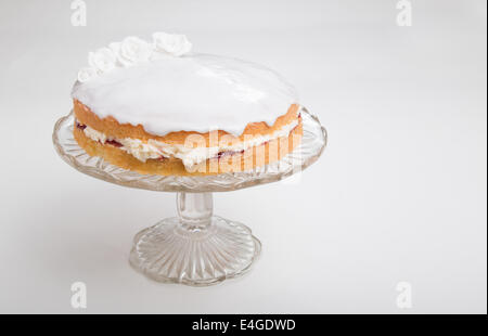 Éponge victoria et rempli de blanc glacé blanc avec des roses à la main sur socle en verre cake stand [Terre] "faire un gâteau de 44'(40) Banque D'Images