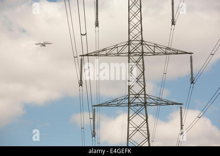 Un avion voler au-delà d'un pylône d'électricité comme il arrive en terre à City airport, London, UK. Banque D'Images