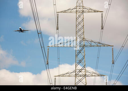 Un avion voler au-delà d'un pylône d'électricité comme il arrive en terre à City airport, London, UK. Banque D'Images