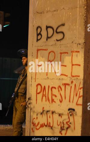 Bethléem, CISJORDANIE PALESTINE- 2014/07/10- Un des soldats israéliens s'appuie contre la Watch Tower militaire au Tombeau de Rachel, également connu sous le nom de Checkpoint 300. Pour la 9ème nuit consécutive de jeunes Palestiniens ont définitivement sortir pour protester contre l'agression d'Israël à Gaza, baptisée opération : Bord de protection, ainsi que des tensions latentes à l'occupation militaire de la Cisjordanie et de Gaza. 9 jeunes Palestiniens ont été blessés, dont un a été touché au pied par une balle réelle. Les soldats israéliens ont été très rapides pour sévir contre les jets de pierre de la jeunesse, tirant des rafales de gaz lacrymogènes de jeeps blindés, de l'eau 'skunk' Banque D'Images