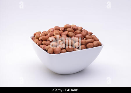 Arachides organise dans le bol isolé sur fond blanc Banque D'Images