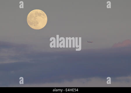 Middletown, New York, USA. 11 juillet, 2014. La presque pleine lune se lève à travers les nuages comme un jet, à droite, les mouches passé comme vu de Middletown, New York. Crédit : Tom Bushey/ZUMA/Alamy Fil Live News Banque D'Images