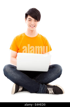 Happy young student sitting on floor and using laptop Banque D'Images