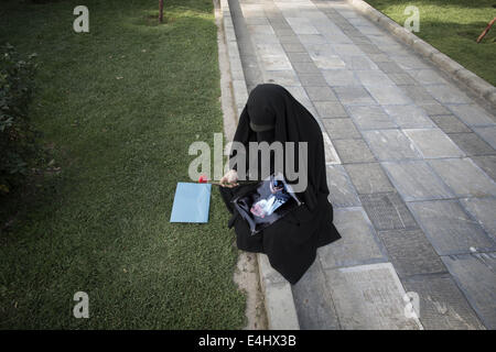 Téhéran, Iran. 12 juillet, 2014. 12 juillet 2014 - Téhéran, Iran - l'Iran une femme voilée est titulaire d'une rose rouge et un portrait de Chef suprême de l'Iran, l'Ayatollah Ali Khamenei, lors d'un rassemblement à l'appui de l'hijab (vinaigrette) Code islamique dans le parc Mellat (Nation) dans le nord de Téhéran. Morteza Nikoubazl/ZUMAPRESS : Morteza Nikoubazl Crédit/ZUMA/Alamy Fil Live News Banque D'Images