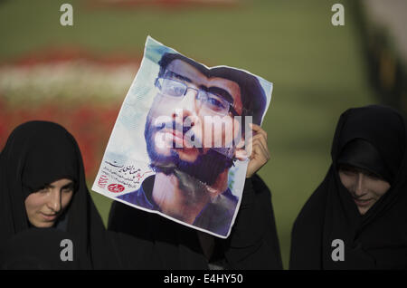 Téhéran, Iran. 12 juillet, 2014. 12 juillet 2014 - Téhéran, Iran - l'Iran une femme voilée est titulaire d'un placard avec un portrait de l'imam Ali, tué iranien KHALILI, qui est connu comme le martyr de Nahi Anil Munkar, pendant un rassemblement à l'appui de l'hijab (vinaigrette) Code islamique dans le parc Mellat (Nation) dans le nord de Téhéran. Morteza Nikoubazl/ZUMAPRESS : Morteza Nikoubazl Crédit/ZUMA/Alamy Fil Live News Banque D'Images