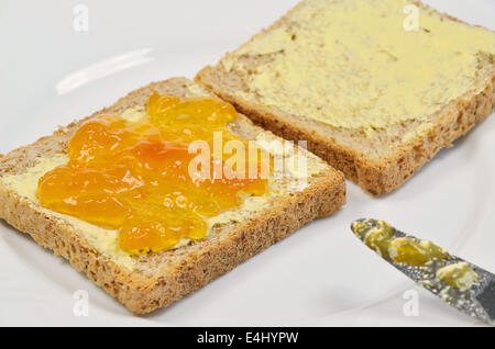 Deux tranches de pain grillé avec confiture d'abricot et de beurre sur la plaque blanche, Close up, full frame Banque D'Images