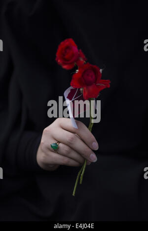 Téhéran, Iran. 12 juillet, 2014. Une femme iranienne détient roses rouges comme le signe de l'amitié alors qu'il participait à une manifestation en soutien du hijab (code vestimentaire islamique) dans le parc Mellat, dans le nord de Téhéran. © Morteza Nikoubazl/ZUMA/Alamy Fil Live News Banque D'Images