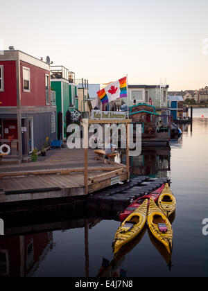 Un Canada Gay Pride Flag flotte sur les bateaux et kayaks moored at Fisherman's Wharf de Victoria, Colombie-Britannique, Canada. Banque D'Images