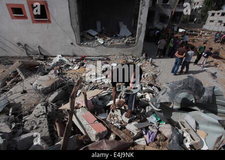 La ville de Gaza, bande de Gaza, territoire palestinien. Le 13 juillet, 2014. Inspecter les décombres de Palestiniens Tayseer Al-Batsh, la maison de la famille qui a annoncé la police a été détruit dans une frappe aérienne israélienne à Gaza, le 13 juillet 2014. La frappe aérienne israélienne sur l'accueil de Al-Batsh, chef de la police de la bande de Gaza, ont tué 18 personnes le samedi, le ministère de la santé de Gaza a déclaré, et le Hamas a tiré le plus grand salvo de roquettes sur Tel Aviv depuis le début de l'offensive de l'état juif dans l'enclave palestinienne. Banque D'Images