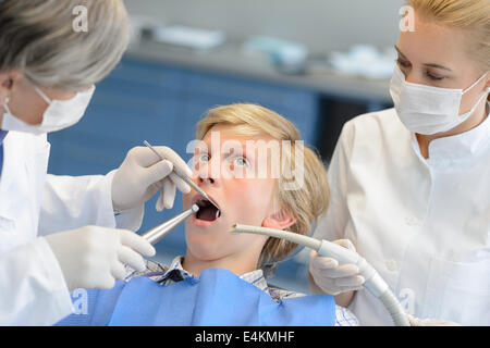 Dentiste et assistant avec peur teenage patient ouvert bouche checkup Banque D'Images