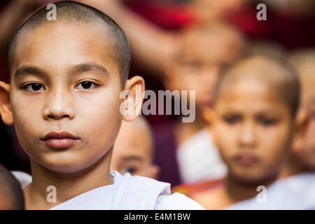 Les jeunes moniales bouddhistes attendre et puis la ligne de participer à une cérémonie d'aumône et repas dans un monastère à Mandalay, Myanmar. Banque D'Images