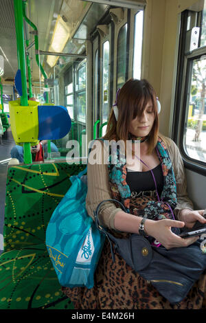 Melbourne Australie, Yarra trams, tram, tramway, tramway, passagers rider riders, rider, femme femme femme, bien habillé, attrayant, écouteurs, assis Banque D'Images