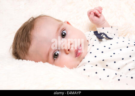 Portrait de magnifique petite fille des taches à haut reposant sur un tapis de fourrure Crème Banque D'Images