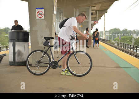 Merrick, New York, USA. 14 juillet, 2014. Pendant l'heure de pointe du soir, un homme avec son vélo attend un train pour arriver sur une plate-forme surélevée de Merrick gare de Babylone, de la direction générale après MTA Metropolitan Transit Authority et Long Island Rail Road Union européenne parle de l'impasse, avec un potentiel d'LIRR imminente grève juste quelques jours auparavant. © Ann Parry/ZUMA/Alamy Fil Live News Banque D'Images