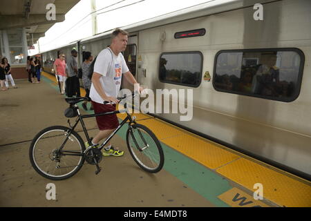Merrick, New York, États-Unis - 14 juillet 2014 - Pendant l'heure de pointe du soir, un homme se promène avec son vélo sur une plate-forme surélevée à bord des trains à Merrick gare de Babylone, de la direction générale après MTA Metropolitan Transit Authority et Long Island Rail Road Union européenne parle de l'impasse, avec un potentiel d'LIRR imminente grève juste quelques jours auparavant. Credit : Ann E Parry/Alamy Live News Banque D'Images