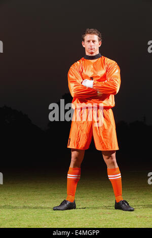 Gardien de but en uniforme orange debout dans un terrain de football Banque D'Images