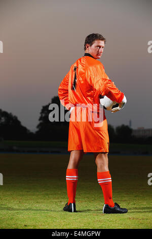 Gardien de but en uniforme orange debout dans un terrain de football Banque D'Images