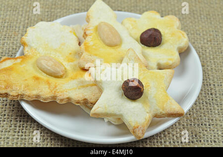 Quatre biscuits de Noël aux amandes et noisettes sur plaque blanche, Close up sur toile Banque D'Images