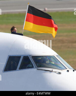 Berlin, Allemagne. 15 juillet, 2014. Le capitaine de vol Uwe Strohdeicher est titulaire d'un drapeau allemand après le débarquement de l'avion transportant l'équipe nationale de football allemande à l'aéroport de Tegel à Berlin, Allemagne, 15 juillet 2014. L'équipe allemande le 13 juillet 2014 avait remporté le Brésil 2014 FIFA World Cup finale contre l'Argentine par 1-0 pour remporter le titre pour la quatrième fois après 1954, 1974 et 1990. Photo : JENS BUETTNER/DPA/Alamy Live News Banque D'Images