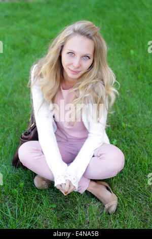 Long-haired girl est assis sur l'herbe Banque D'Images