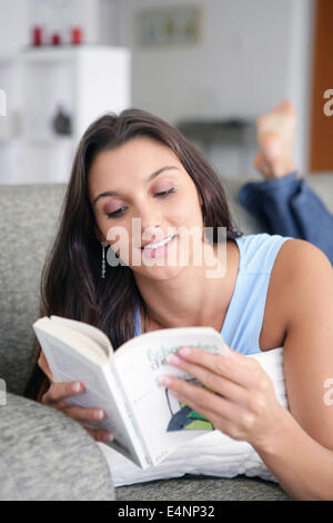 Femme sur un canapé-lit un livre Banque D'Images