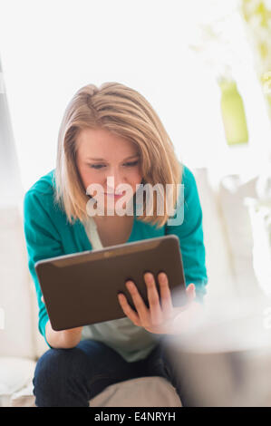 Portrait of woman on sofa using digital tablet Banque D'Images