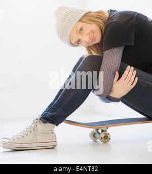 Portrait of young woman sitting on skateboard Banque D'Images