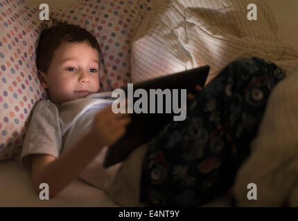 Boy (6-7) using digital tablet in bed Banque D'Images