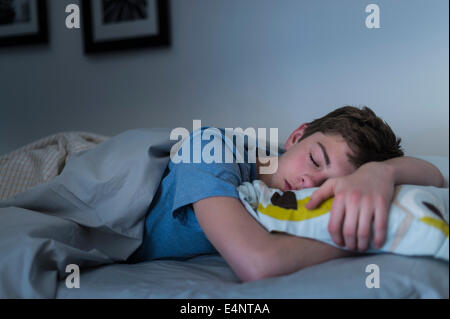 Teenage boy (16-17) sleeping in bed Banque D'Images