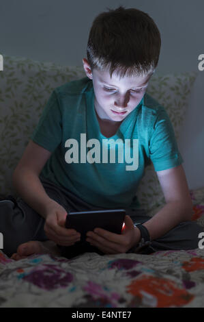 Boy (8-9) using digital tablet in bed Banque D'Images