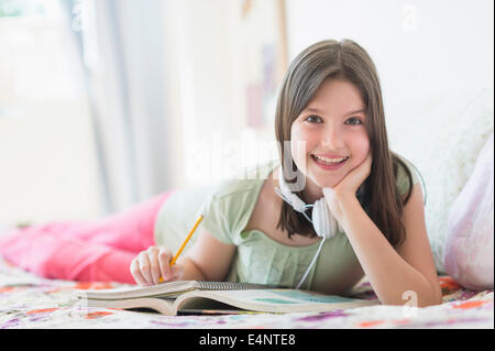 Girl (10-11) au lit et de l'apprentissage Banque D'Images