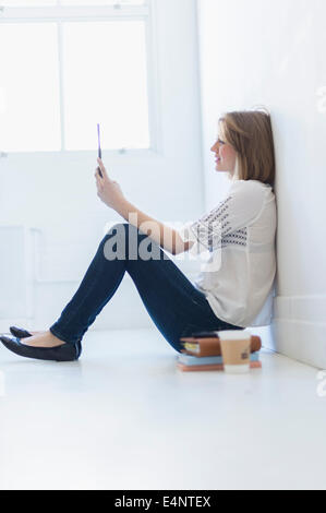 Young woman sitting on floor and using digital tablet Banque D'Images