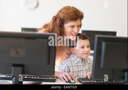 Boy (6-7) et enseignant à l'aide ordinateur Banque D'Images