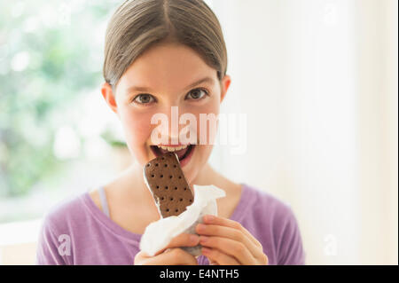 Girl (10-11) eating ice cream sandwich Banque D'Images