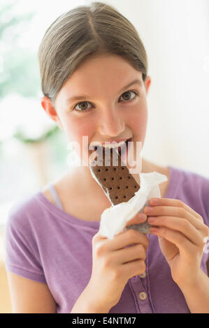 Girl (10-11) eating ice cream sandwich Banque D'Images