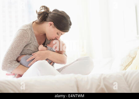 Mother kissing baby boy (2-5 months) in bed Banque D'Images