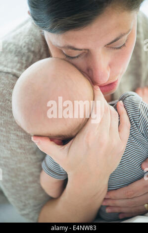 Close up of mother chuchotant à Baby Boy's (2-5 mois) oreille Banque D'Images