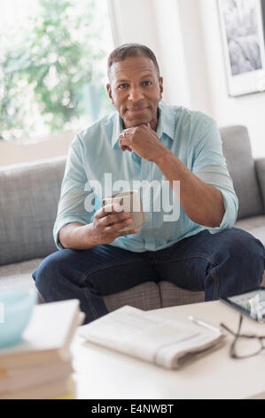 Portrait of man sitting on sofa at home Banque D'Images