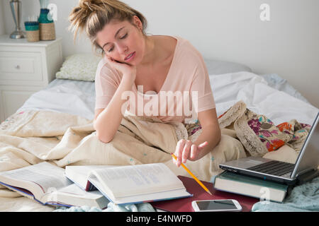 Jeune femme studing in bed Banque D'Images