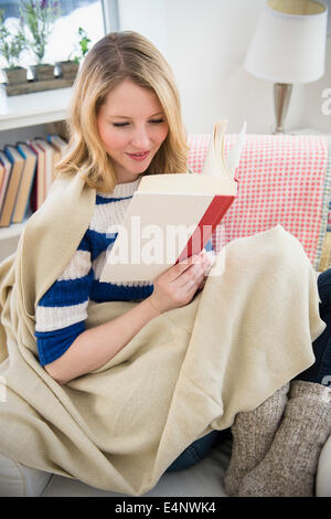 Blonde woman reading on sofa Banque D'Images